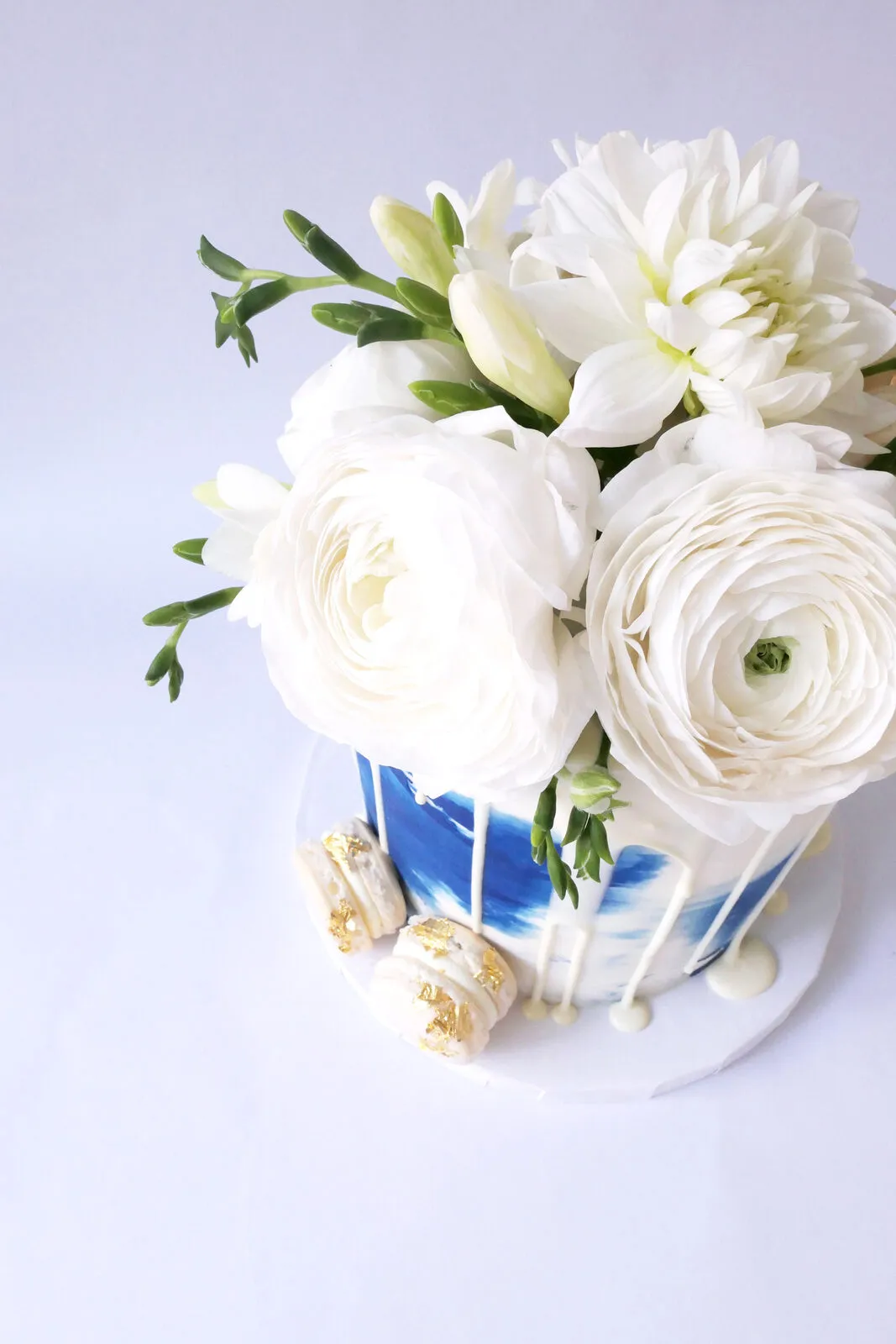 A white cake finished with a hand-painted navy watercolour panel and white ranunculus