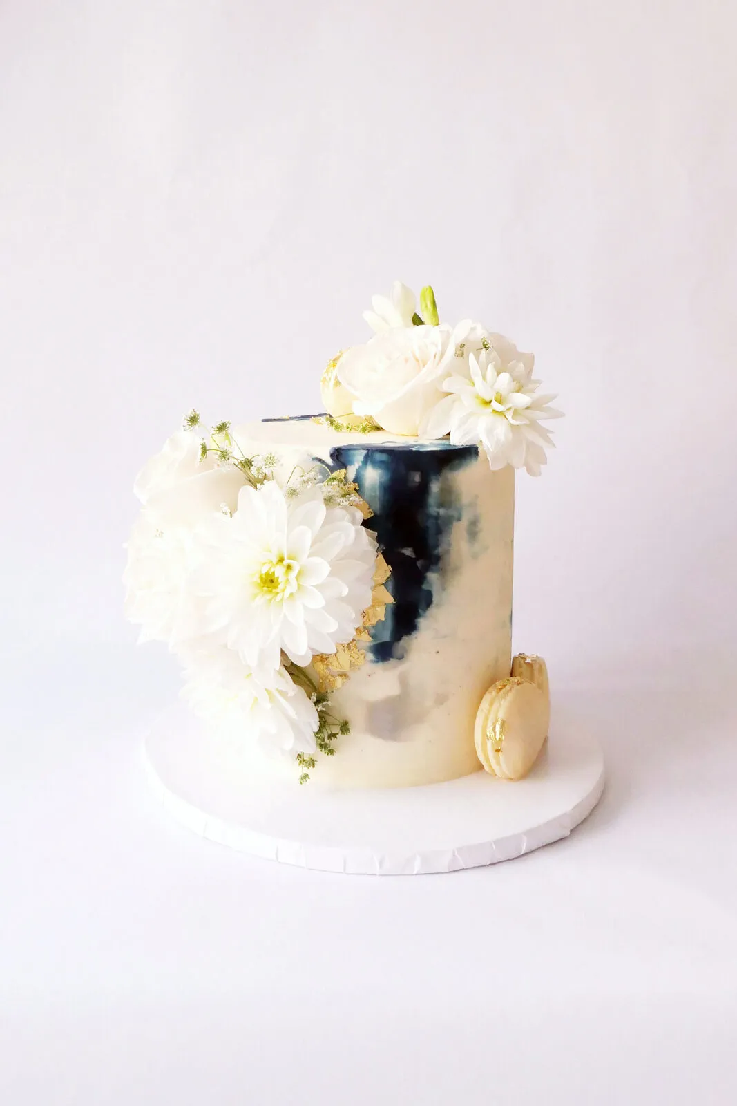 A white cake with a hand-painted navy watercolour panel and white flowers
