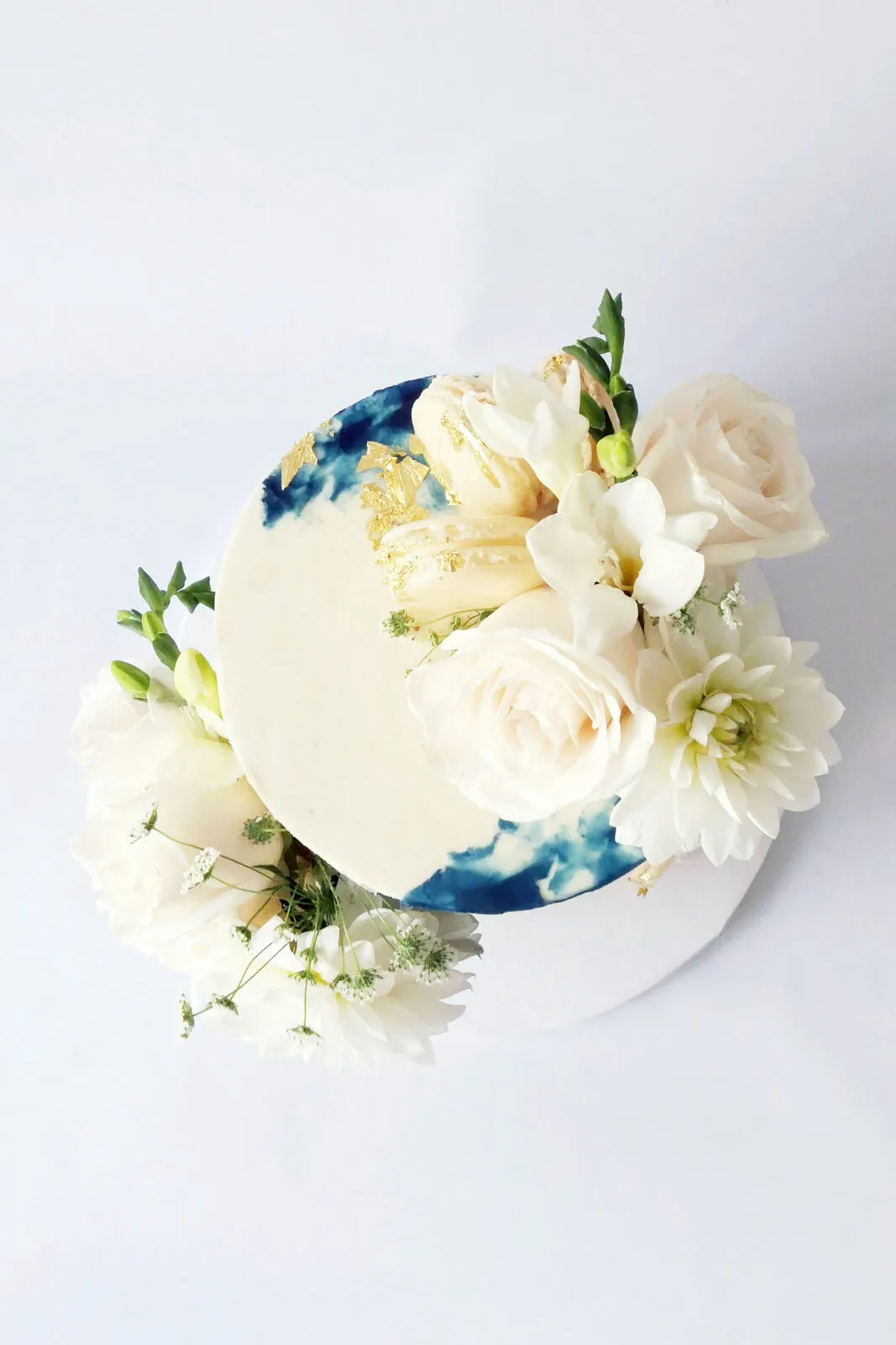 A white cake with a navy watercolour panel and white flowers