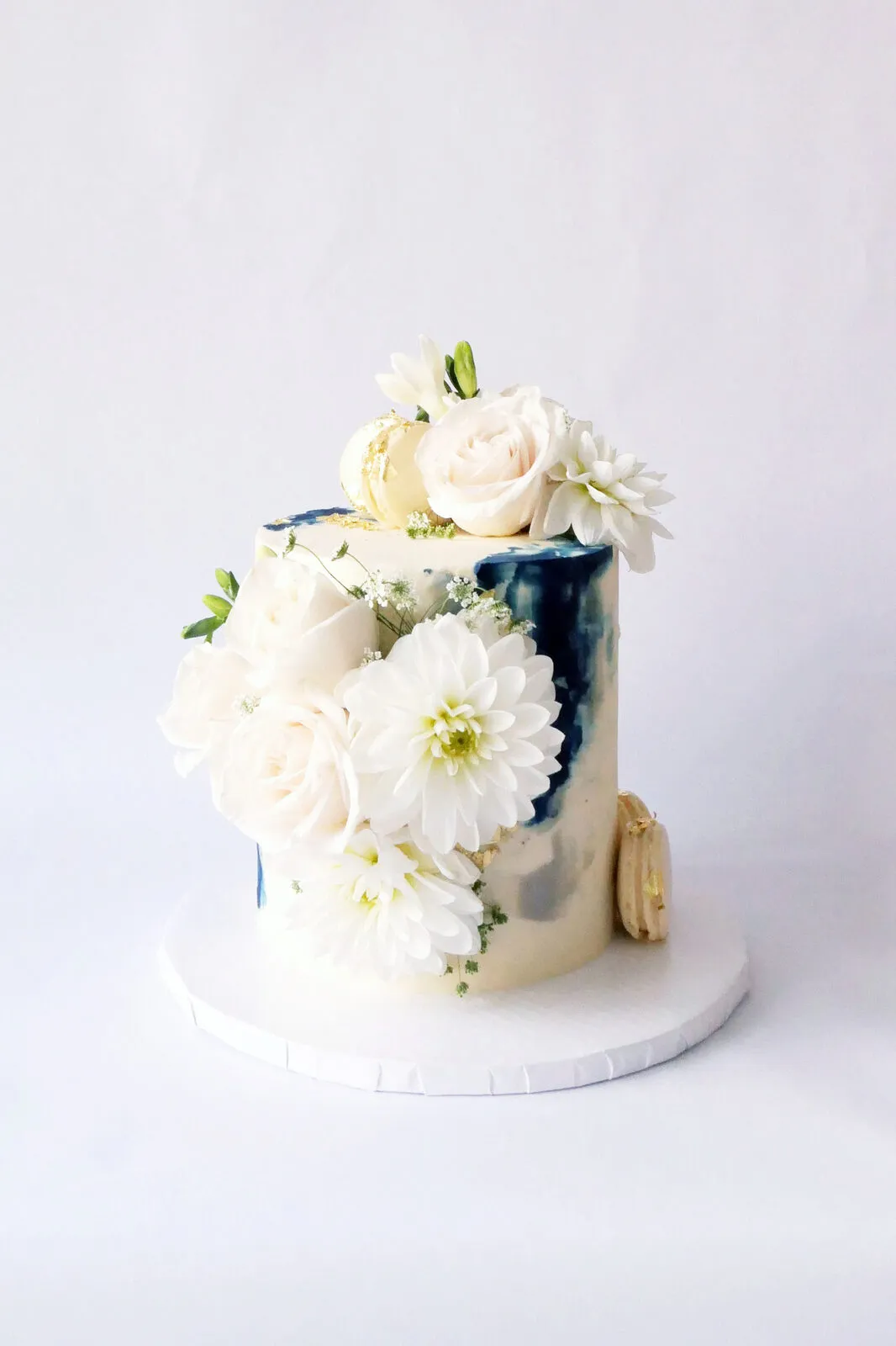 A white cake with a navy watercolour panel and white blooms