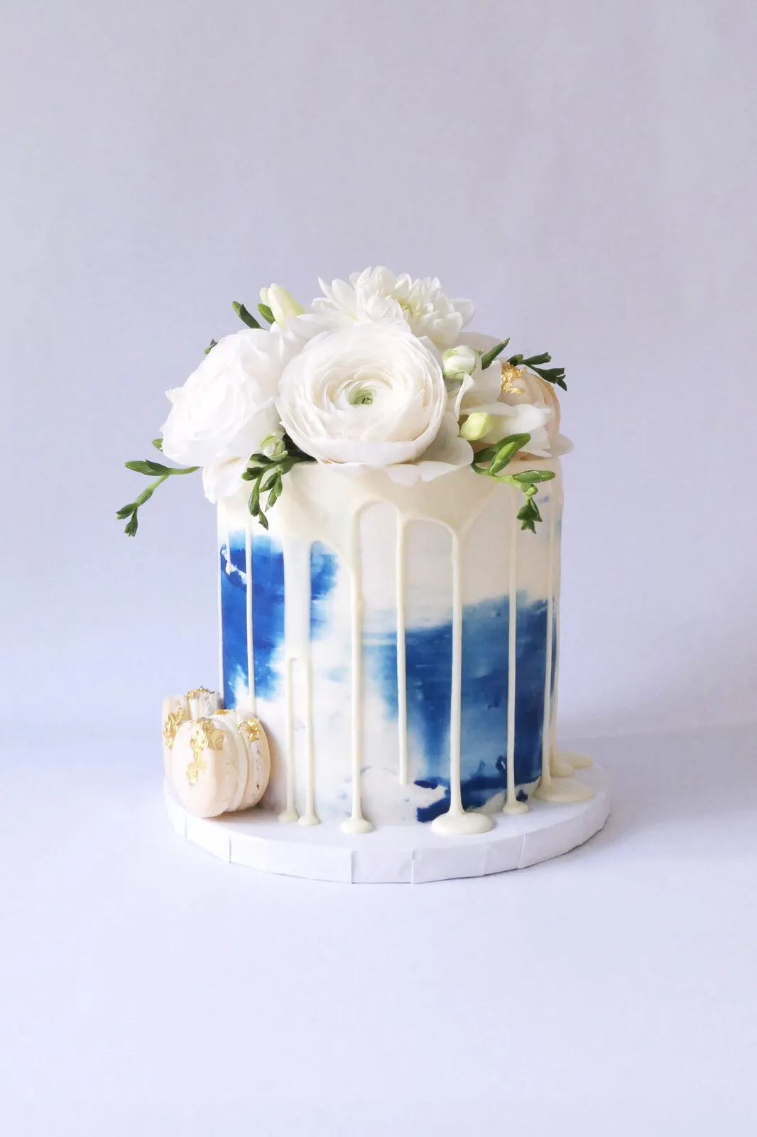 A white cake with a navy drip finish and white blooms