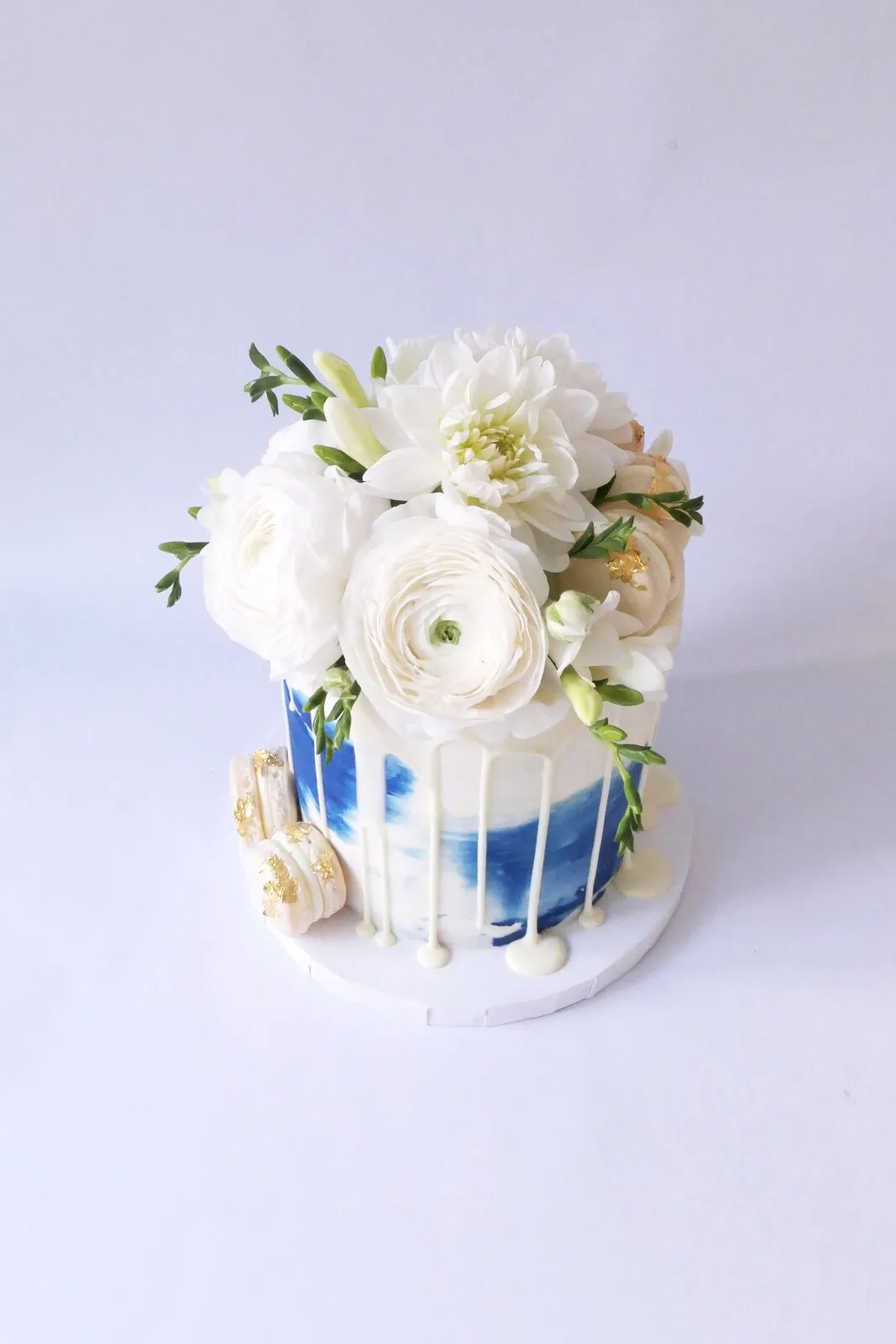 A white cake with a navy drip and cream flowers