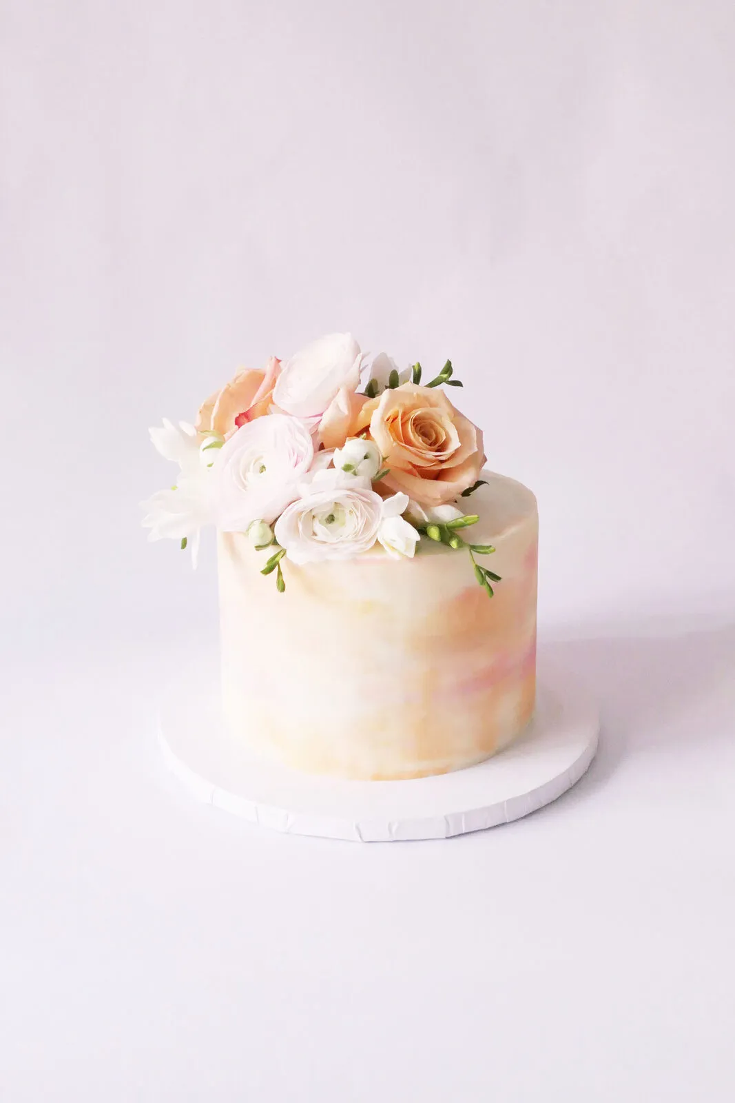 A blush buttercream cake topped with fresh flowers