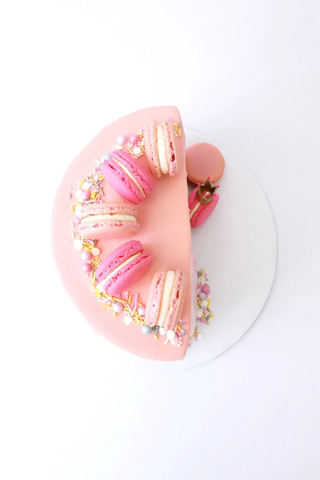 A pink cake finished with macarons and sprinkles