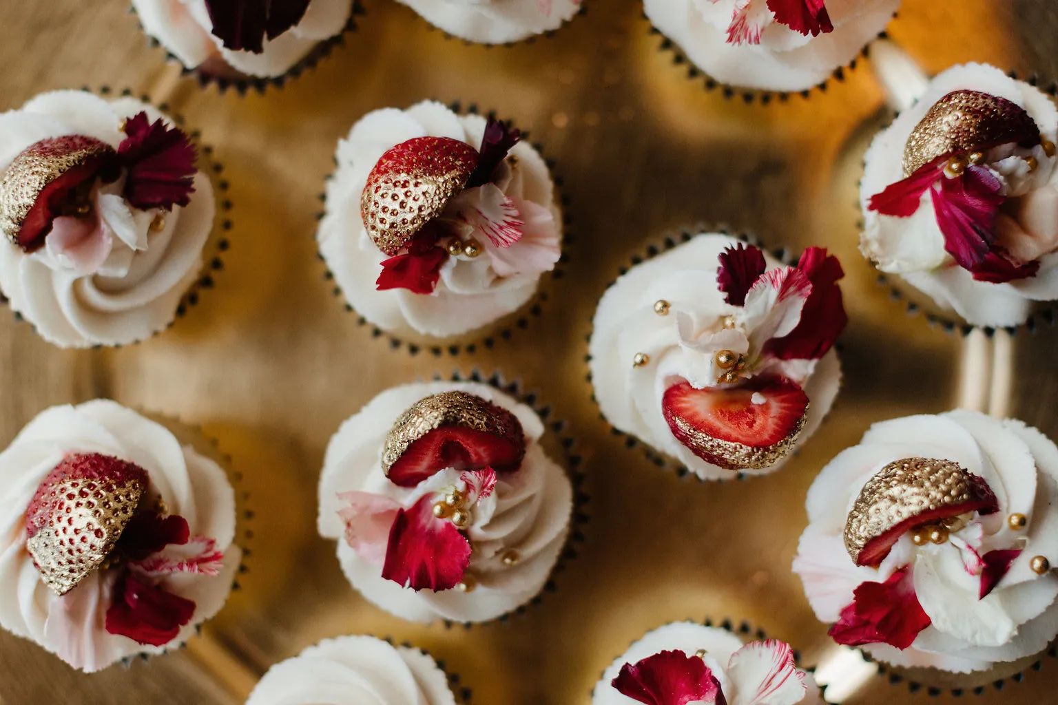 Cupcakes topped with gilded strawberries and flowers